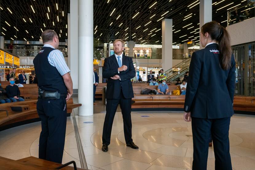 Koning Willem-Alexander in centrale aankomsthal Schiphol in gesprek met enkele medewerkers