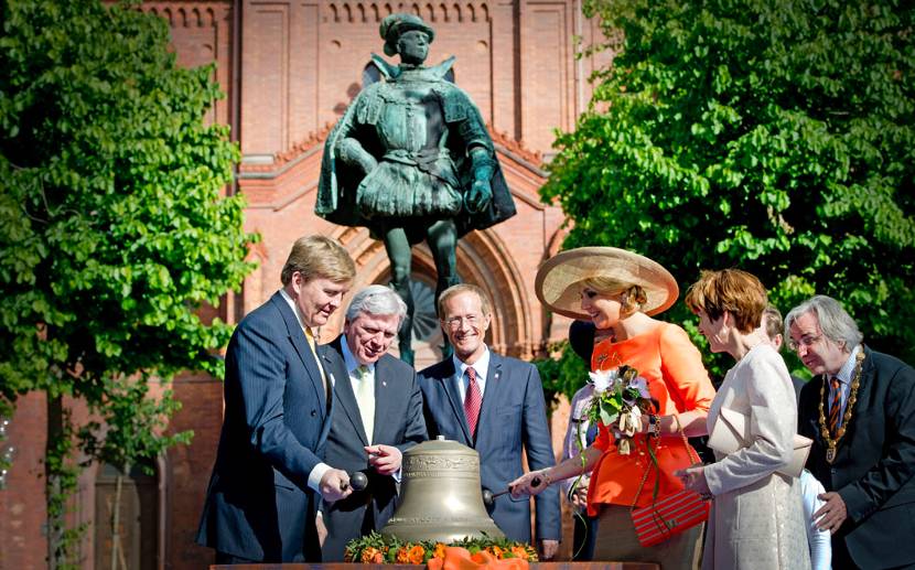 Wiesbaden, 3 juni 2013: Koning Willem-Alexander en Koningin Máxima slaan, bij het standbeeld van Willem de Zwijger, samen met minister-president Volker Bouffier (2eL) en Oberburgemeister van Wiesbaden Helmut Müller (R) de gong op het gerestaureerde carillon van de Marktkirche . 