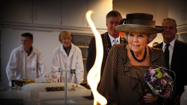 Burgemeester Albert de Hoop van Ameland, Prinses Beatrix en directeur Bernard Kamsma kijken naar een scheikundeproef.