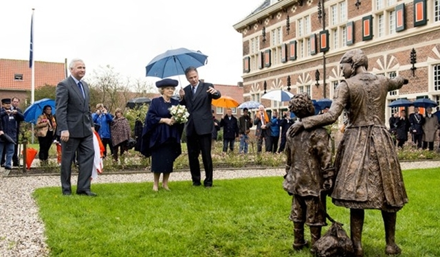 Prinses Beatrix bekijkt een beeld van weeskinderen tijdens haar bezoek aan het Weeshuis te Buren.