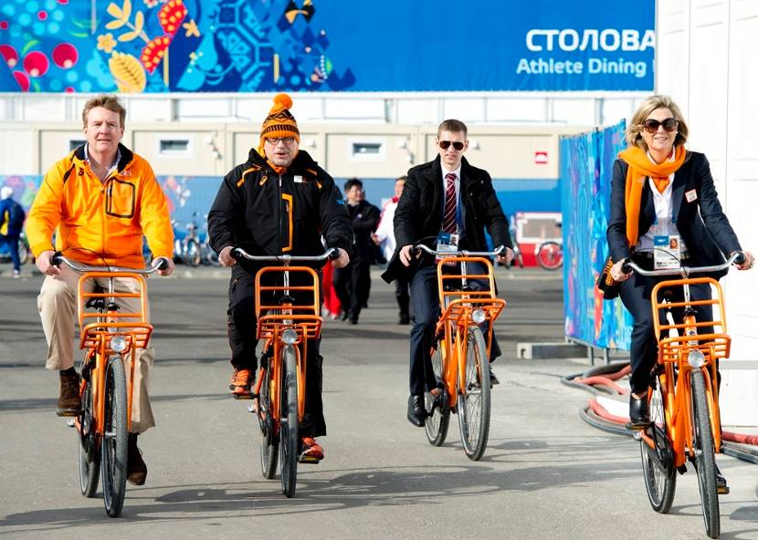 Koning Willem-Alexander, chef de mission Maurits Hendriks en Koningin Máxima fietsen het olympisch dorp uit tijdens de Olympische Winterspelen .
