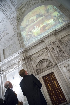 Koning Willem-Alexander en Koning Carl XVI Gustaf bekijken de projectie van een afbeelding van het schilderij De Samenzwering van de Bataven onder Claudius Civilis op de muur in de noordgalerij van het Koninklijk Paleis Amsterdam