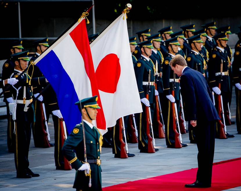 Koning Willem-Alexander buigt voor de Nederlandse en Japanse vlag tijdens de welkomstceremonie op het voorplein bij het Keizerlijk Paleis in Tokio.