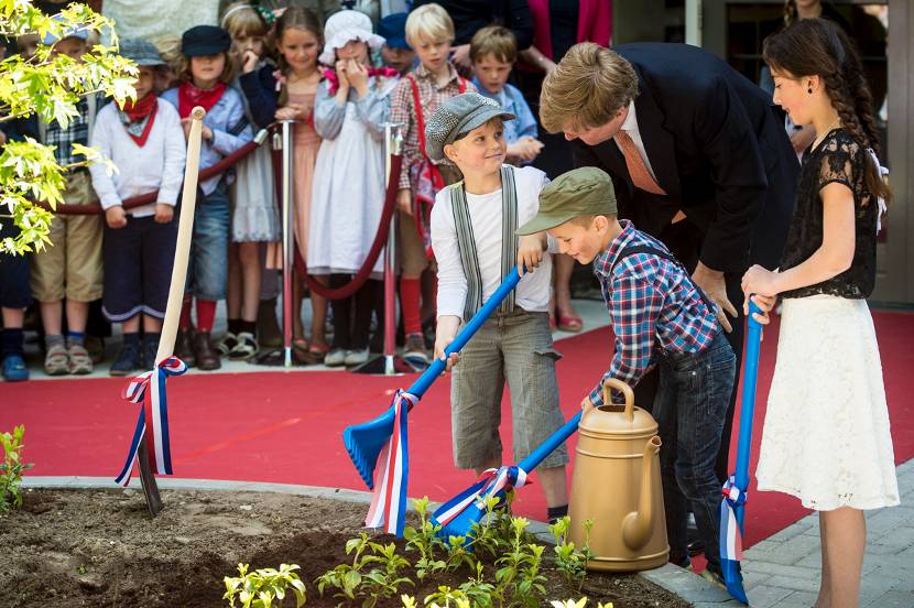 Koning Willem-Alexander steekt samen met drie leerlingen de spade in de grond tijdens de opening van De Nieuwe Baarnsche school (NBS)