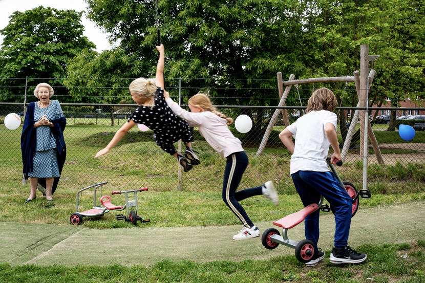 Prinses Beatrix kijkt naar spelende kinderen op de landelijke Buitenspeeldag