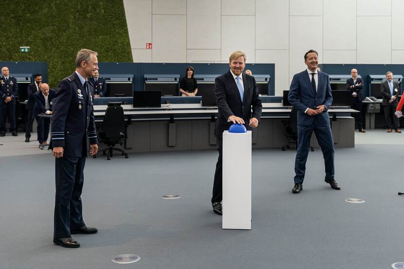 De Koning drukt op een grote blauwe knop bij de opening van het nieuwe radar- en trainingsgebouw Polaris