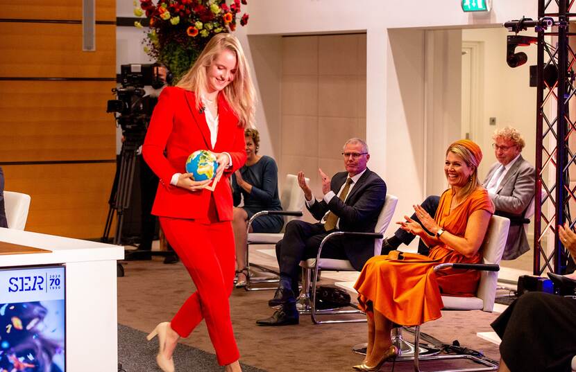 Mevrouw met wereldbol op jubileumcongres SER.