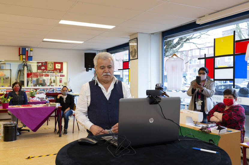 Man voor laptop. Mensen op de achtergrond.