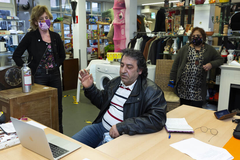 Man in naaiatelier bij laptop.