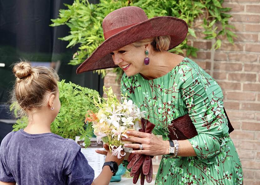 Koningin Máxima ontvangt bloemen van een kind tijdens het streekbezoek aan Salland.