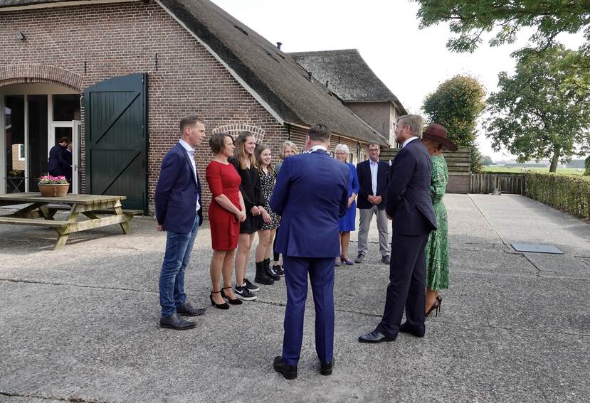 Koning Willem-Alexander en Koningin Máxima in gezelschap op het erf van melkveehouderij IJsselhoeve De Riet.