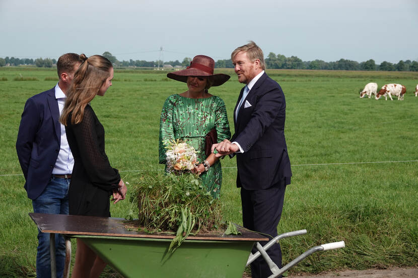 Koning Willem-Alexander en Koningin Máxima in gesprek bij een kruiwagen.