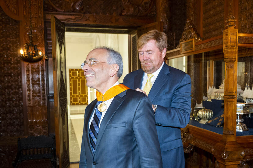 Koning Willem-Alexander doet een medaille om bij Ed Spanjaard