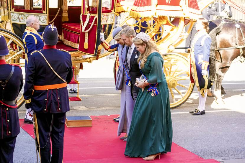 Koning Willem-Alexander, Koningin Máxima en de Prinses van Oranje groeten bij aankomst bij de Koninklijke Schouwburg het vaandel van het Korps Mariniers