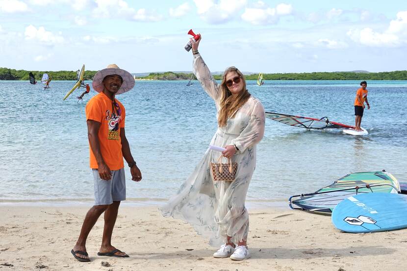 De Prinses van Oranje geeft het startsein voor een windsurfdemonstratie in de Baai van Sorobon