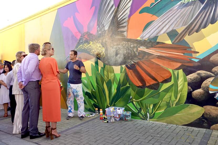 Koning Willem-Alexander, Koningin Máxima en de Prinses van Oranje bij een muurschildering in San Nicolas in Aruba