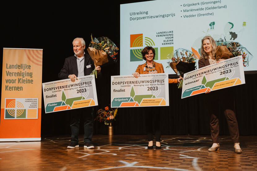 Tijdens het symposium 'Zorg op het Dorp' wordt de Dorpsvernieuwingsprijs uitgereikt, bedoeld voor initiatieven van bewoners en om succesvolle acties voor het versterken van de voorzieningen in dorpen te belonen. De winnaar een finalisten staan op het podium tijdens de uitreiking.